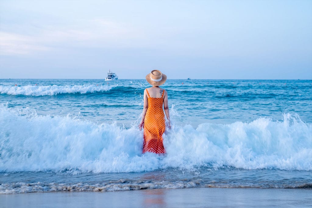 Lady dressed in orange skirt is walking in the ocean