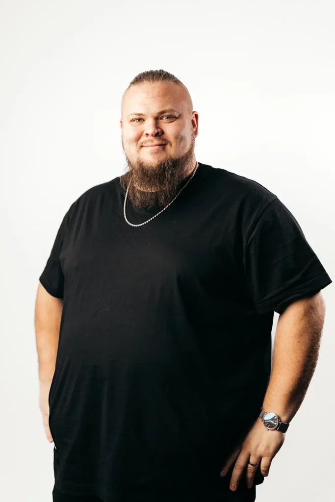 Mikael Hugg studiokuvassa valkoisen seinän edessä